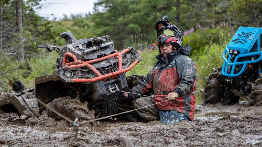 man and atv in the mud